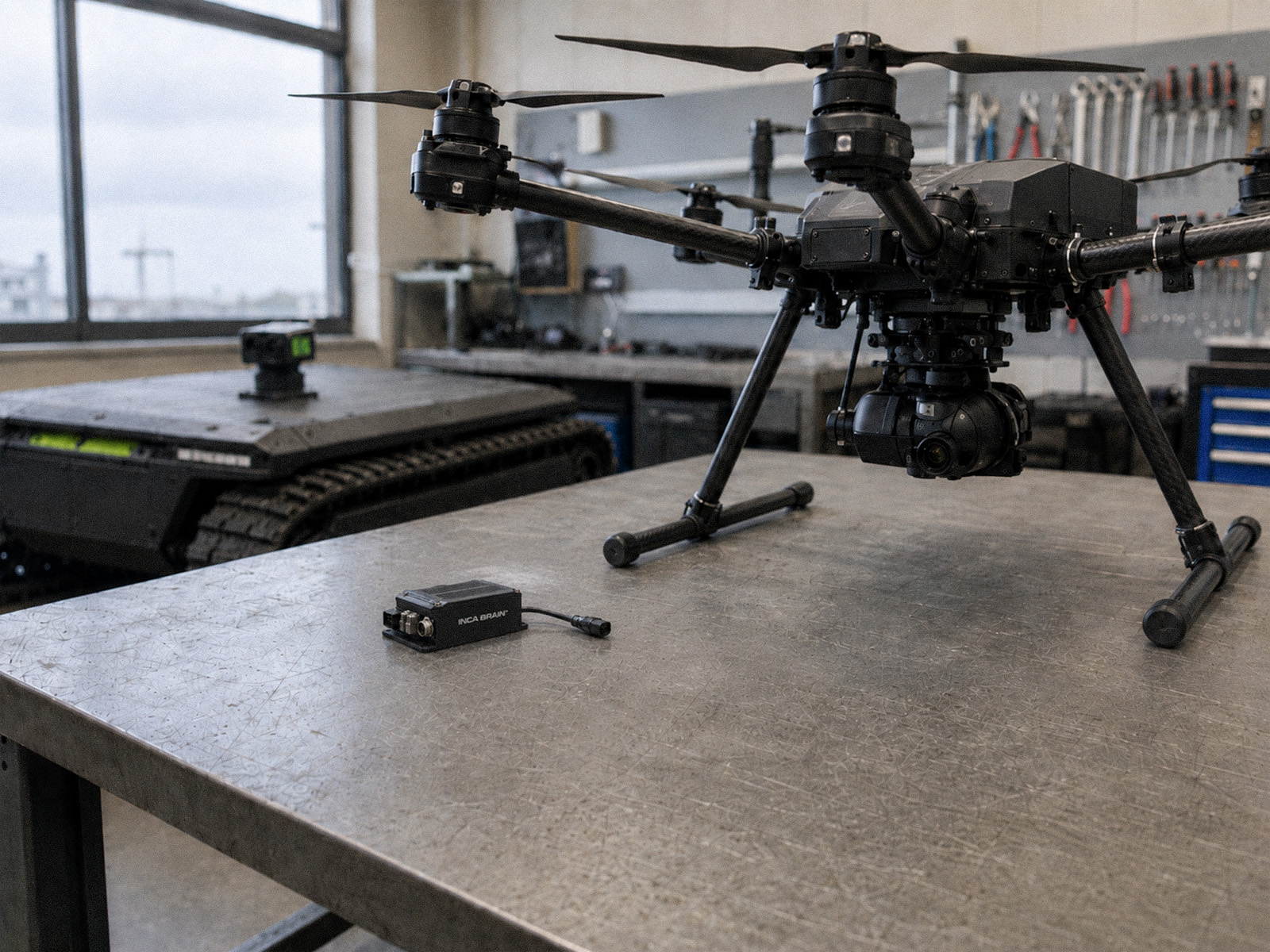 INCA Brain module on a workbench next to a large drone in a workshop.