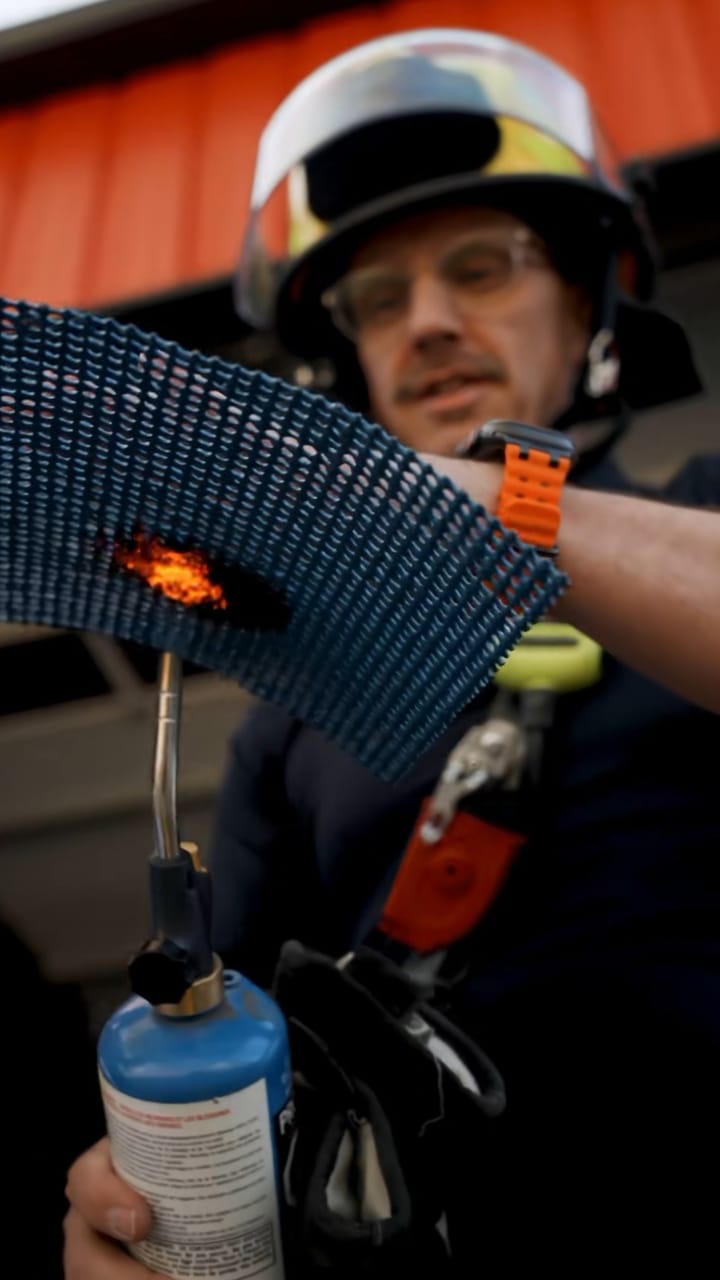 Firefighter holding a gas torch to a sheet of blue coated INCA WFS net®