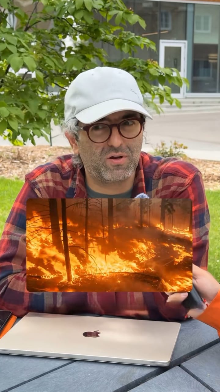 Man holding a tablet showing a photo of a wildfire