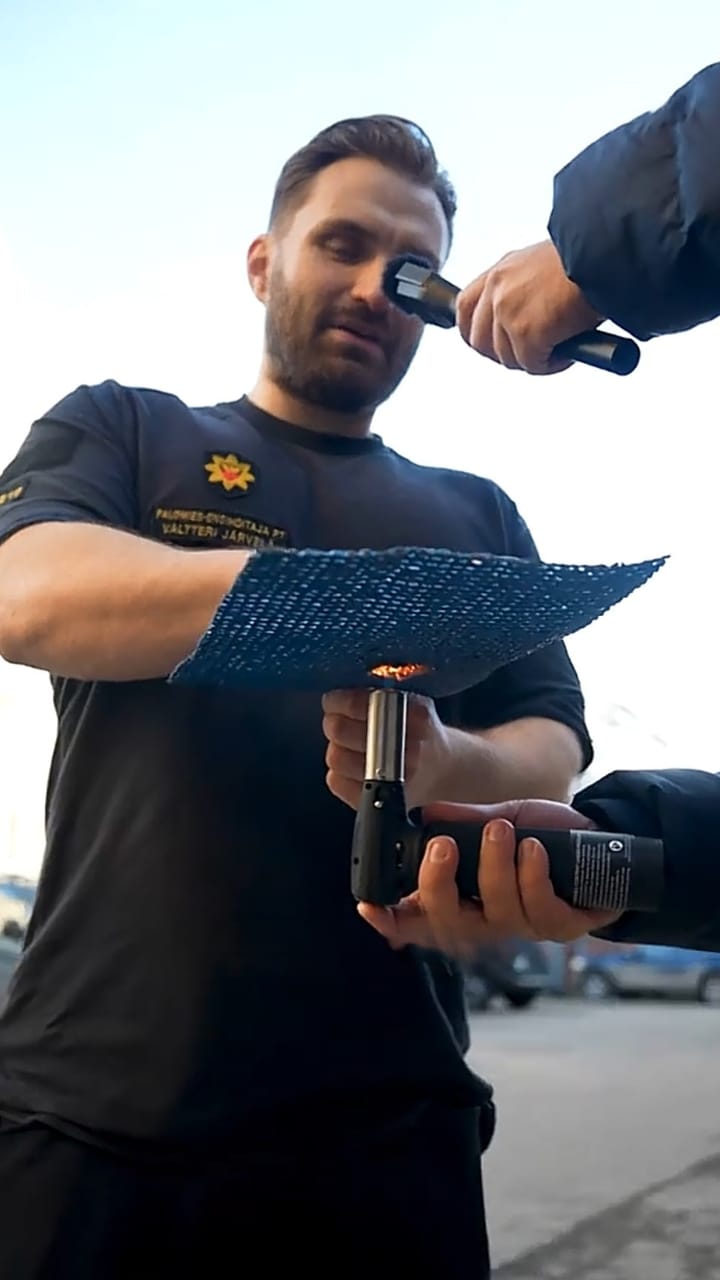 Firefighter holding a gas torch to a sheet of blue coated INCA WFS net®
