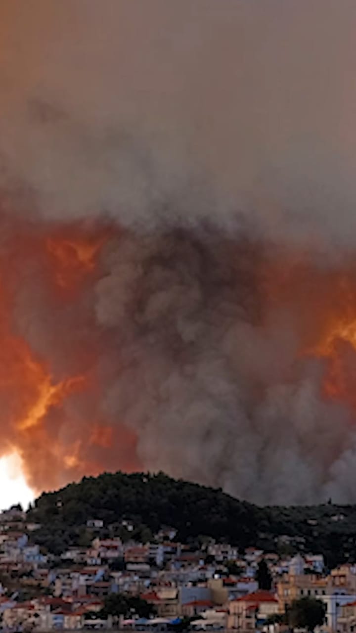 Smoke and flames from a wildfire rising over a hillside town