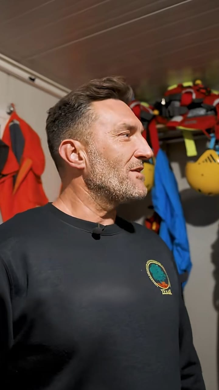 Volunteer firefighter in a fire station with protective gear hanging behind him