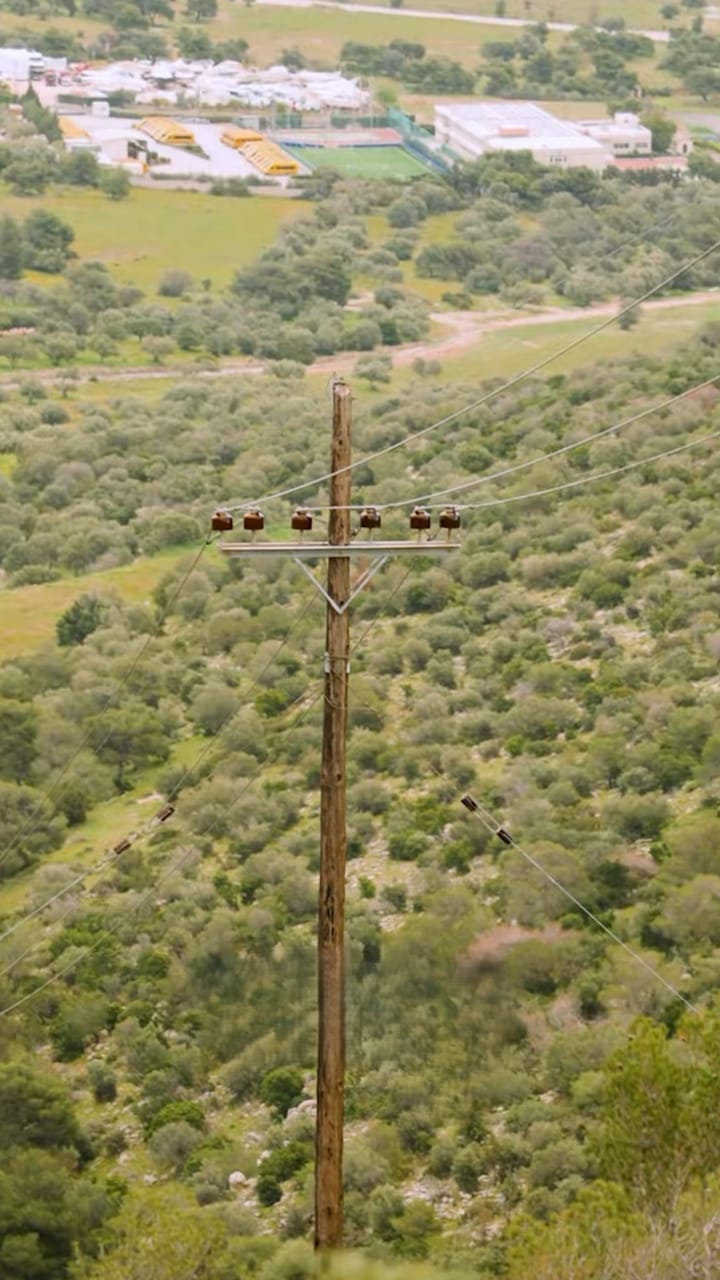 Wooden power line pole on a green hillside