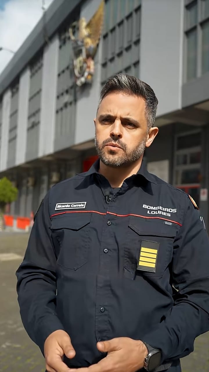 Portuguese firefighter in a dark uniform outside a fire station