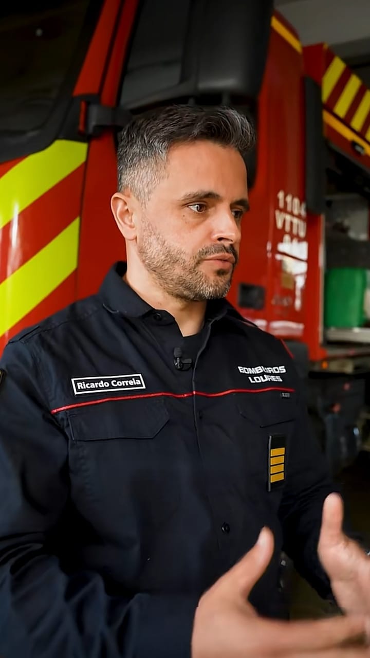 Portuguese firefighter speaking in front of a fire engine