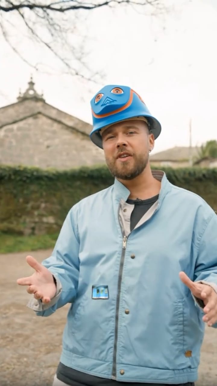 Presenter in a blue INCA helmet in a village with old stone buildings
